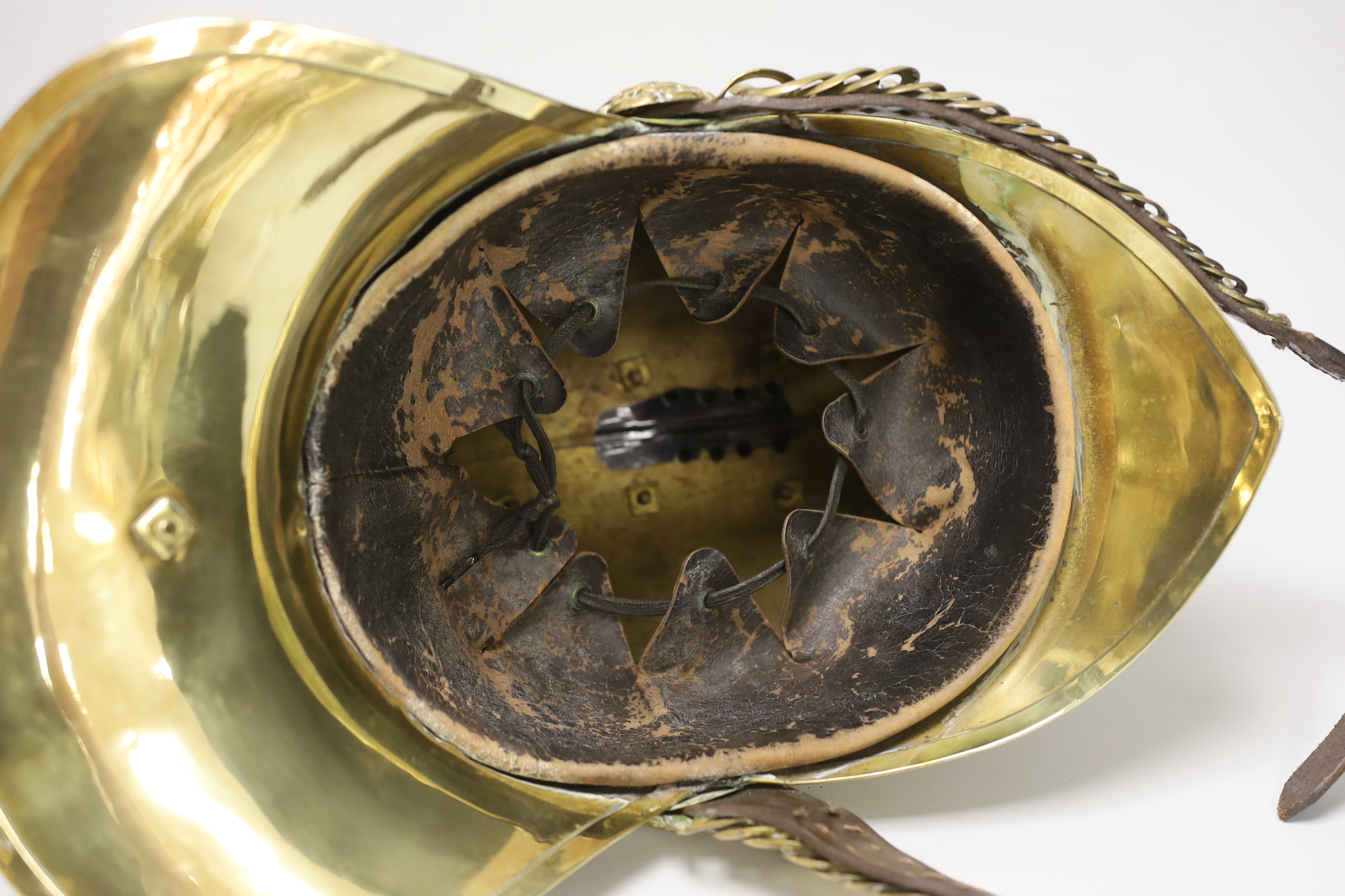A late 19th/early 20th century brass Merryweather fire brigade helmet with embossed decoration and leather liner, 34cm in length